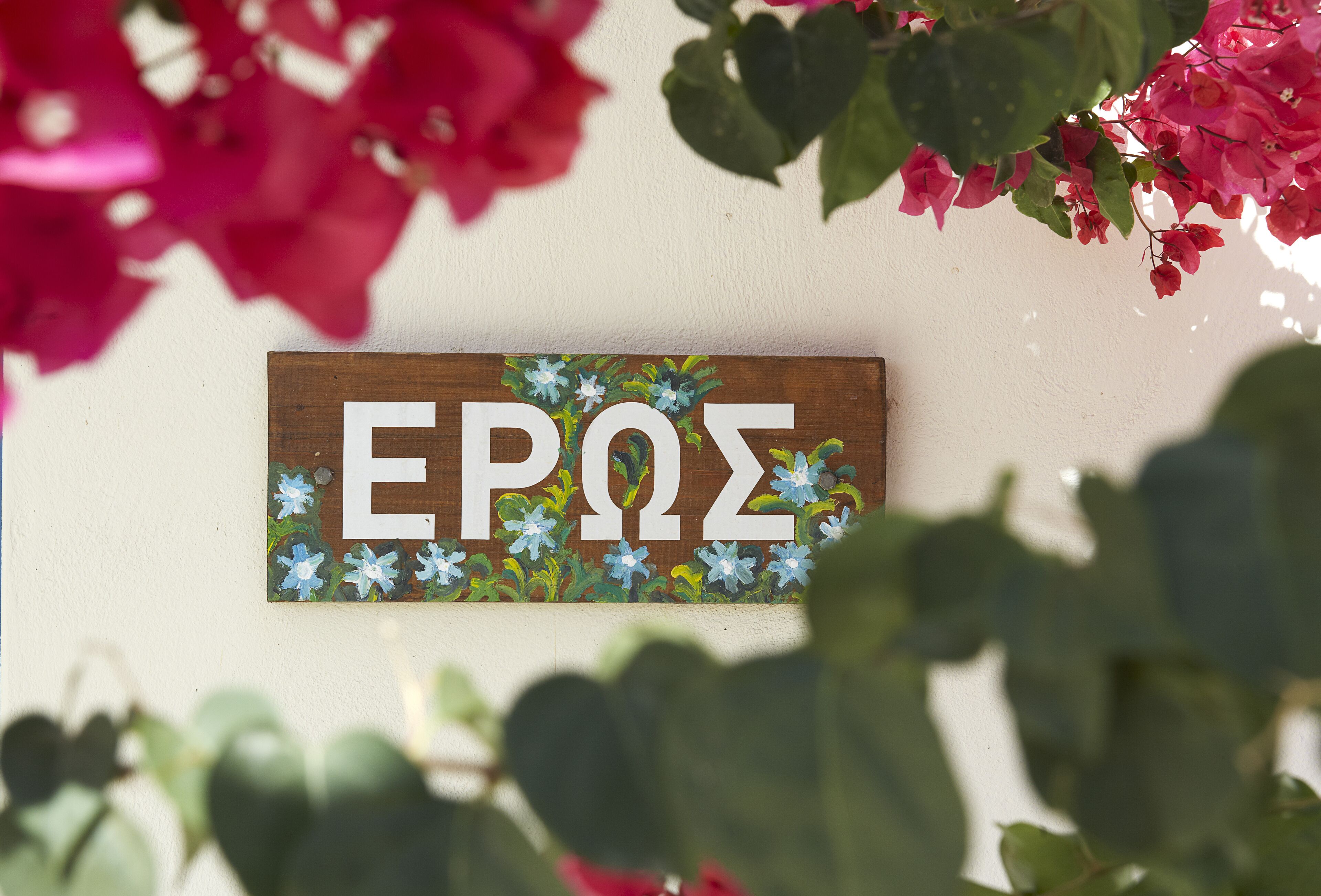 Een houten bord met de letters 'EPΣ' en een bloemistisch ontwerp.