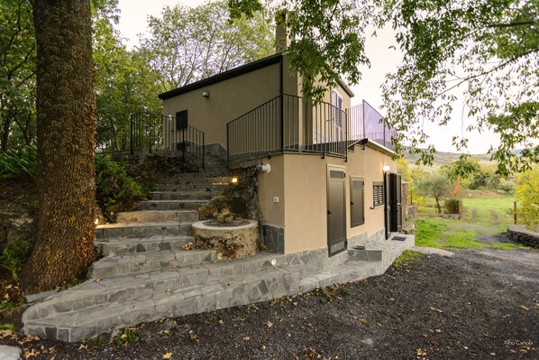 A two-story house with a stone staircase leading to a balcony.