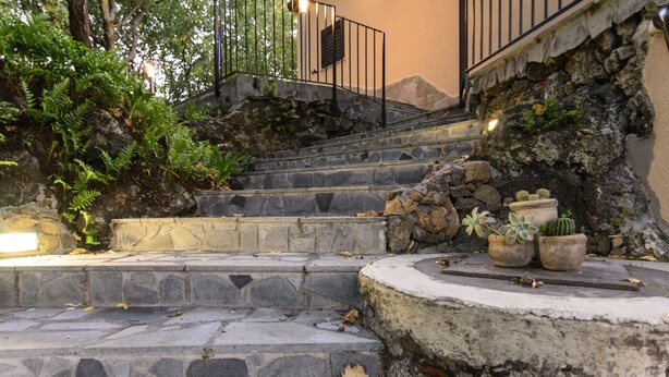Una escalera de piedra con diseño rústico que lleva a una barandilla de metal.
