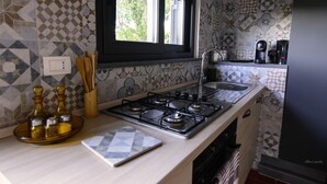 Una cocina con estufa a gas, ventana, pileta y cafetera.