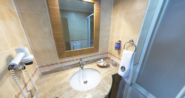 A bathroom with a sink, mirror, towel rack, and a hairdryer. - Tamara Otel (Van)