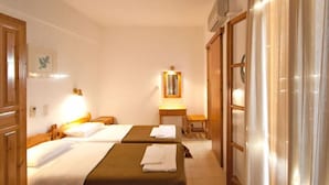 A hotel room with two beds, a small table, a mirror, and a window with curtains.