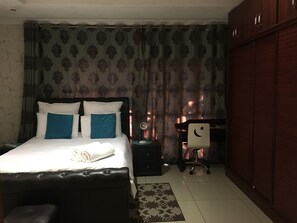 Ein Hotelzimmer mit Bett, Schreibtisch, Stuhl und Kleiderschrank.