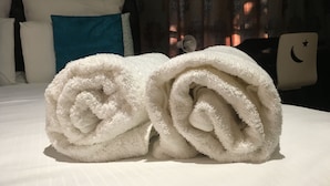 A neatly made bed with white linens and a blue pillow. - Blomsbed Inn (Palapye)