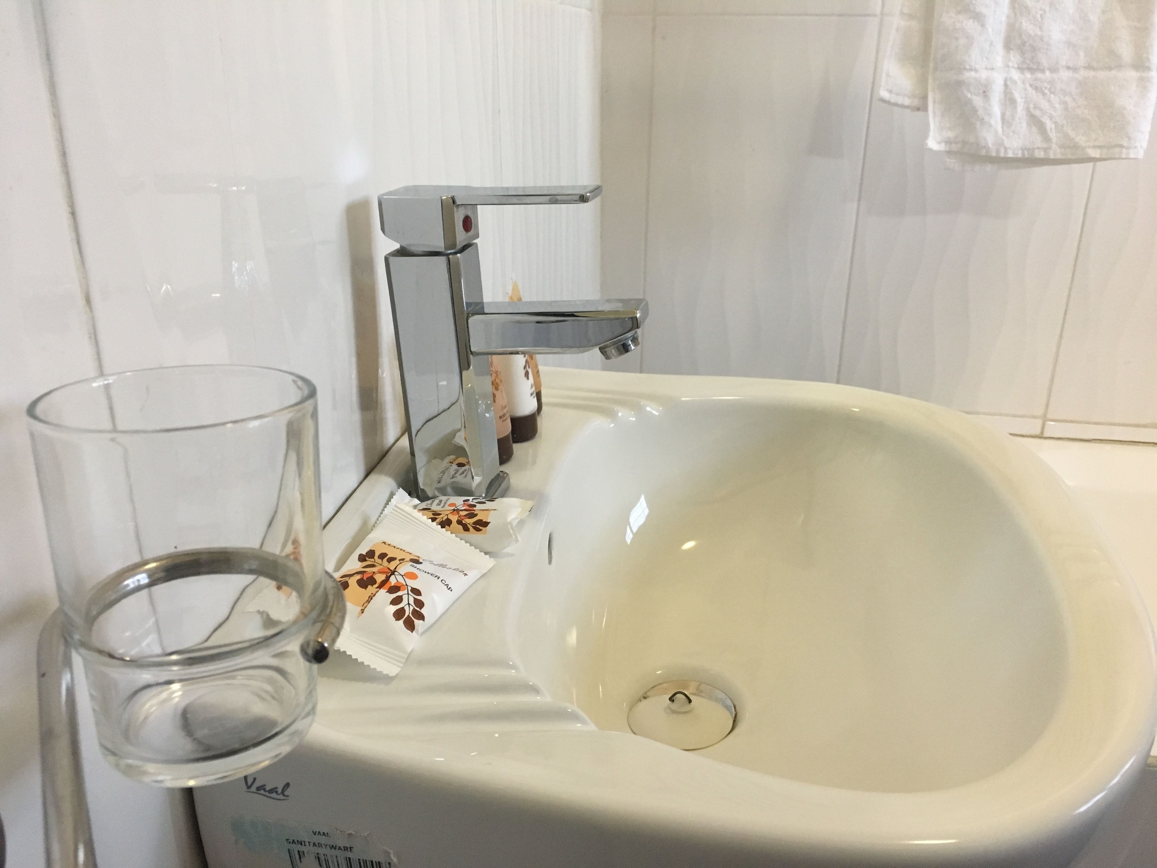Un lavabo con un vaso y un paquete de artículos de aseo.
