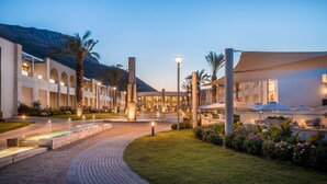 A modern hotel with a central courtyard, outdoor seating, and a mountain backdrop.