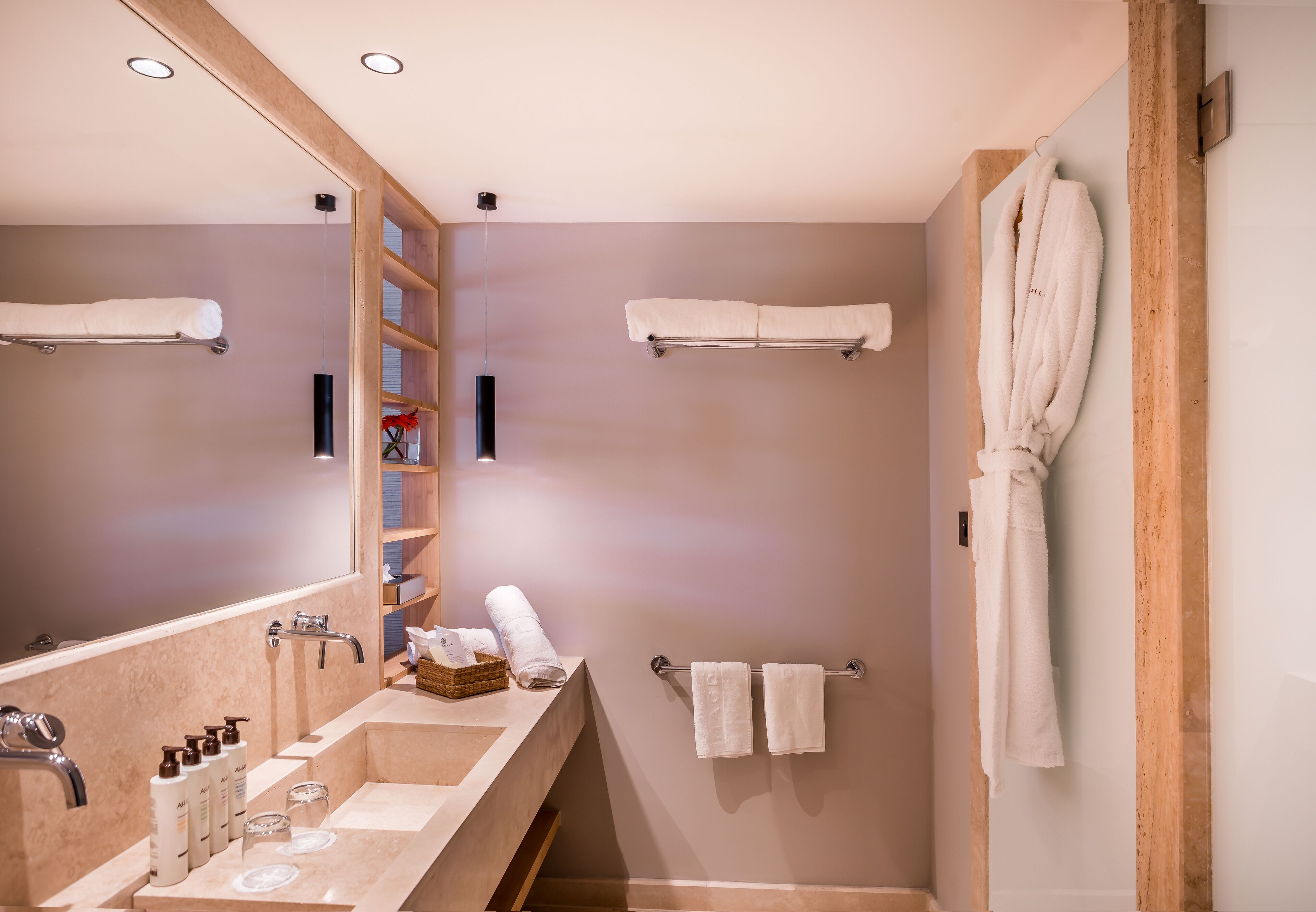 A modern bathroom with a large mirror, a sink with toiletries, and a towel rack.