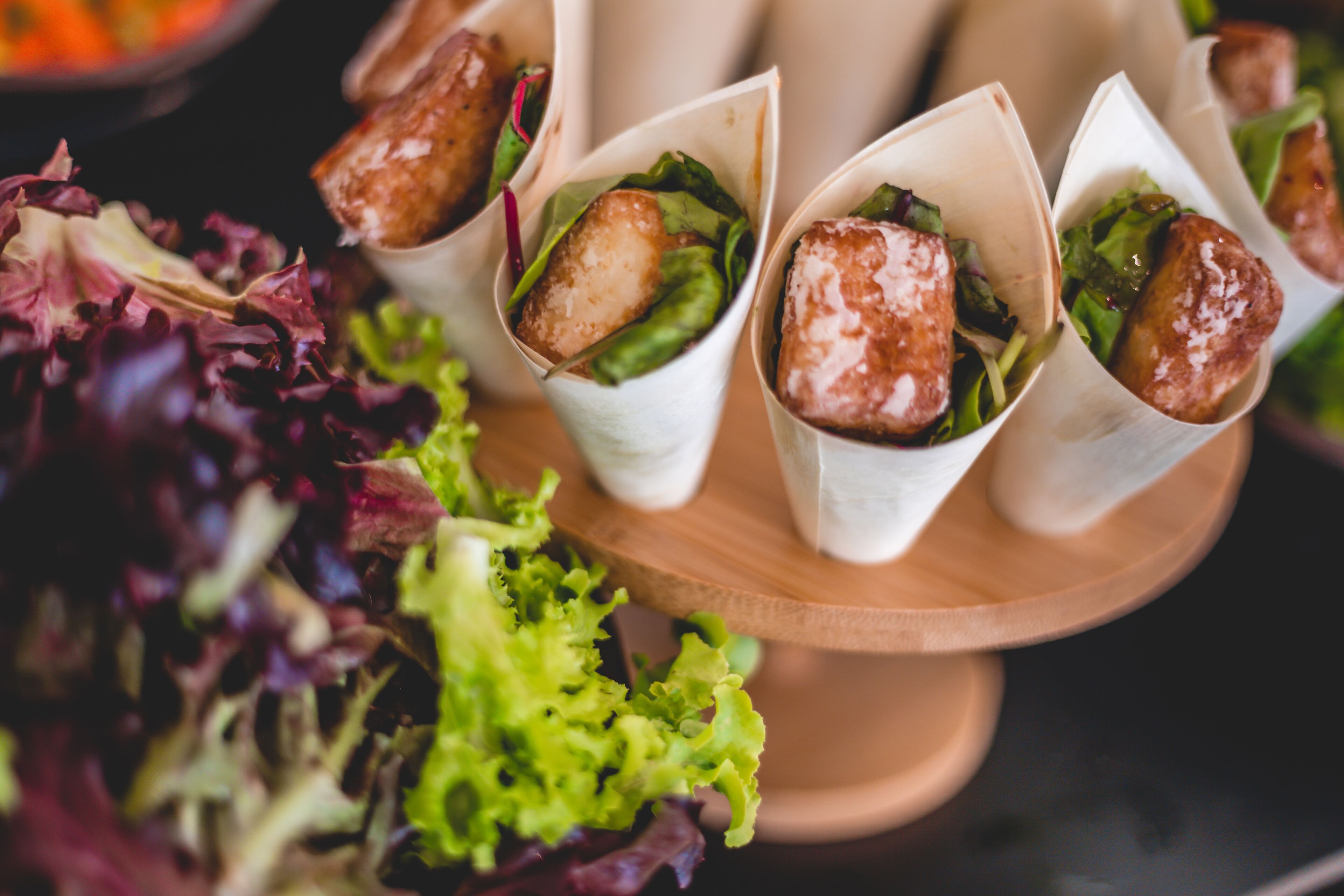 A tray of food items, likely appetizers, arranged on a wooden stand.