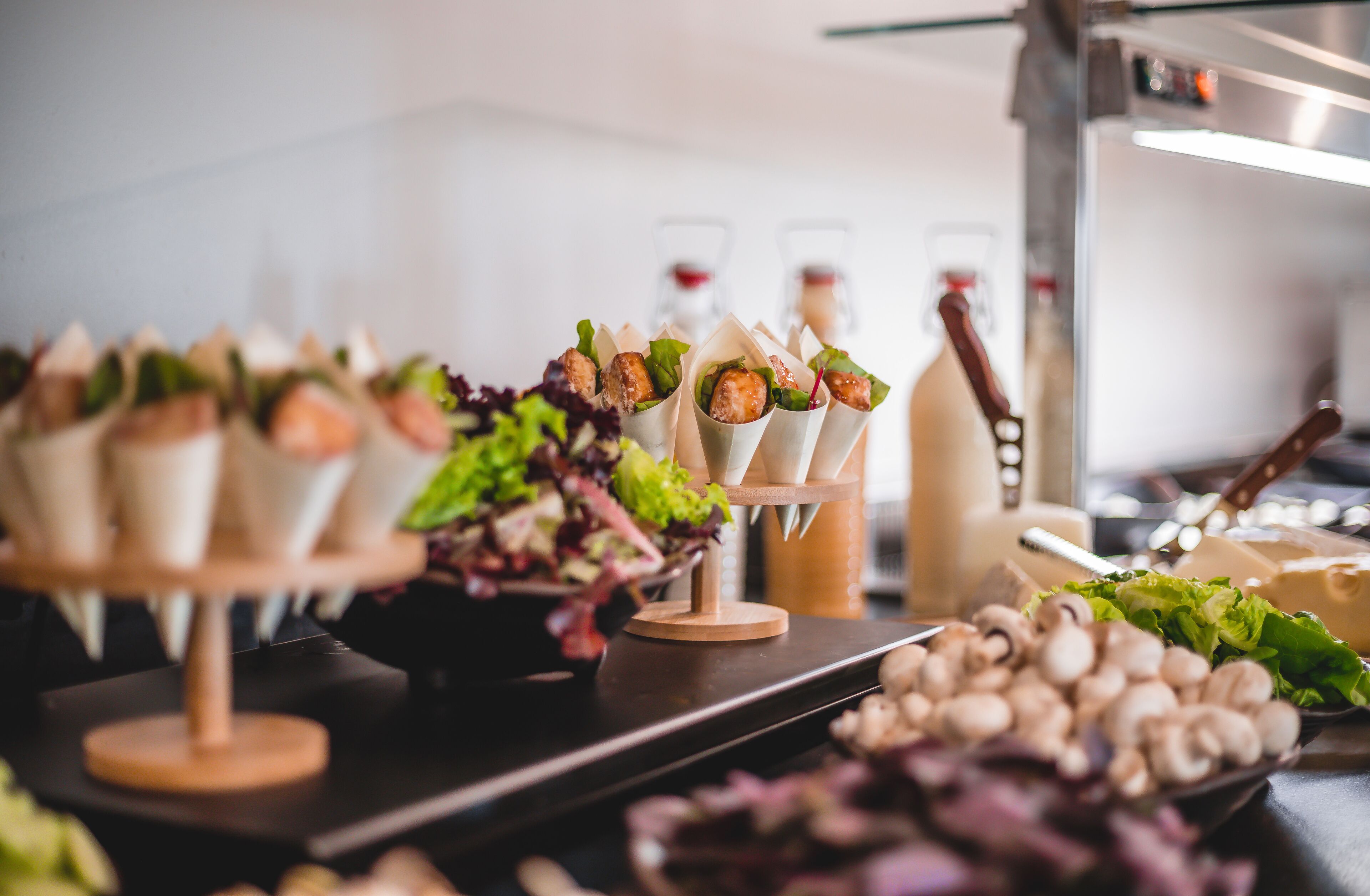 Una mesa de buffet con alimentos como champiñones y verduras, y una botella de vino al fondo.