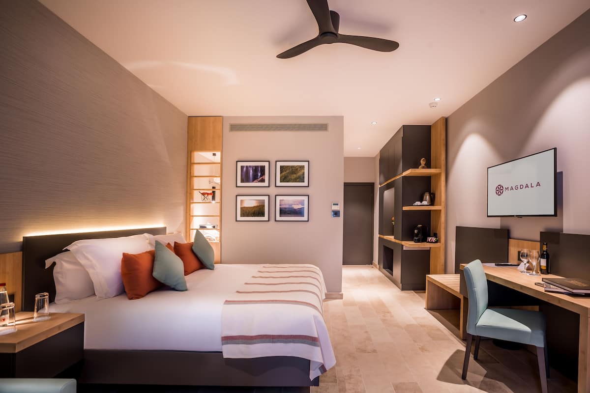 Ein modernes Hotelzimmer mit einem großen Bett, einem Schreibtisch und einem Deckenventilator.