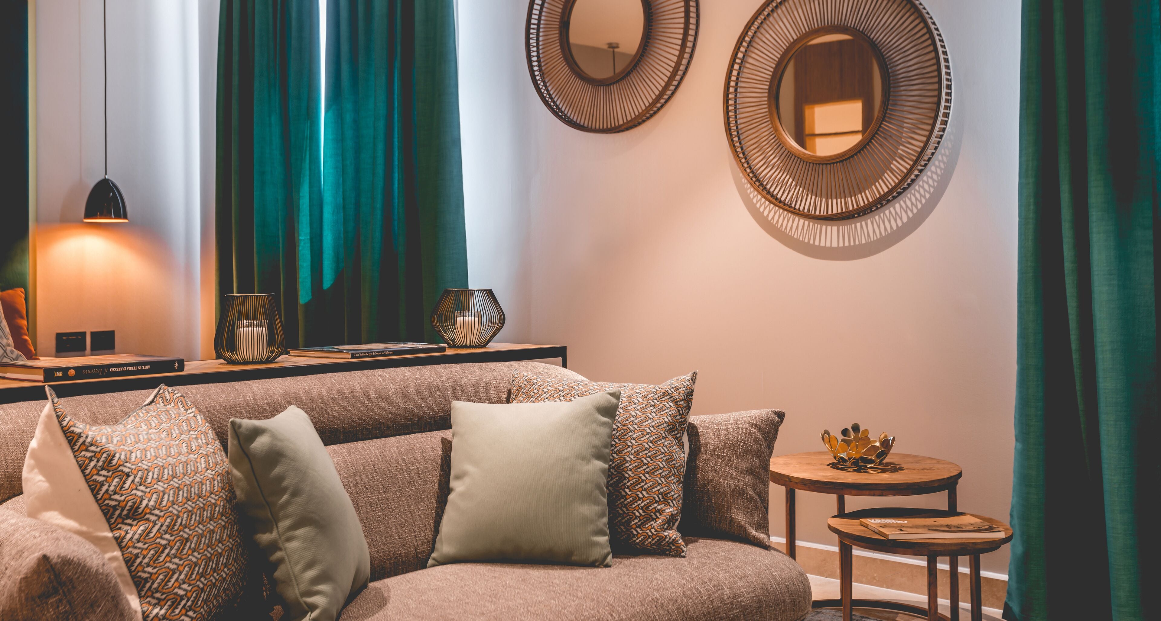 A cozy living room with a sofa, pillows, a small round table, and two wall-mounted mirrors.