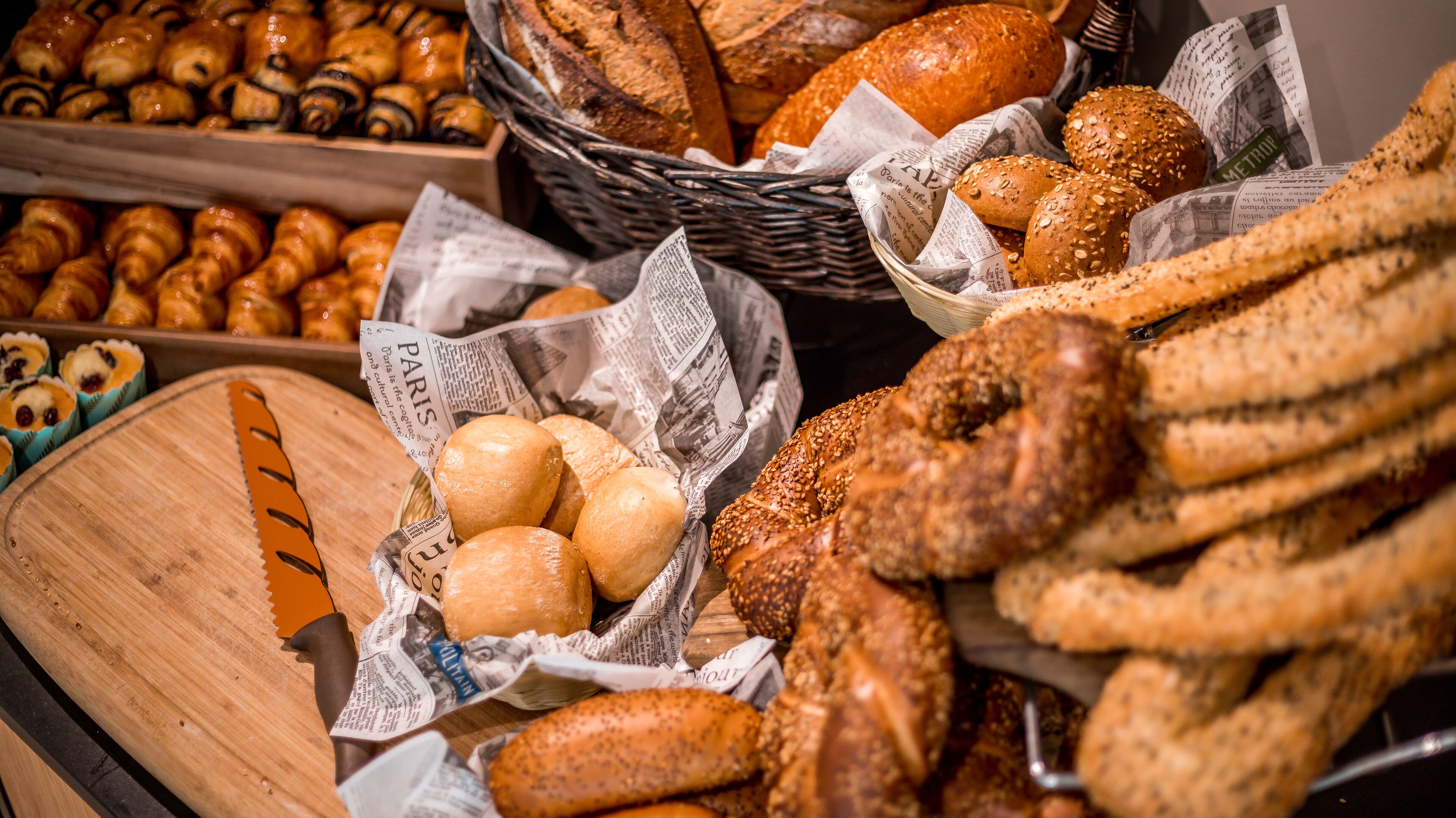 A variety of breads and pastries displayed in baskets and on wooden boards.