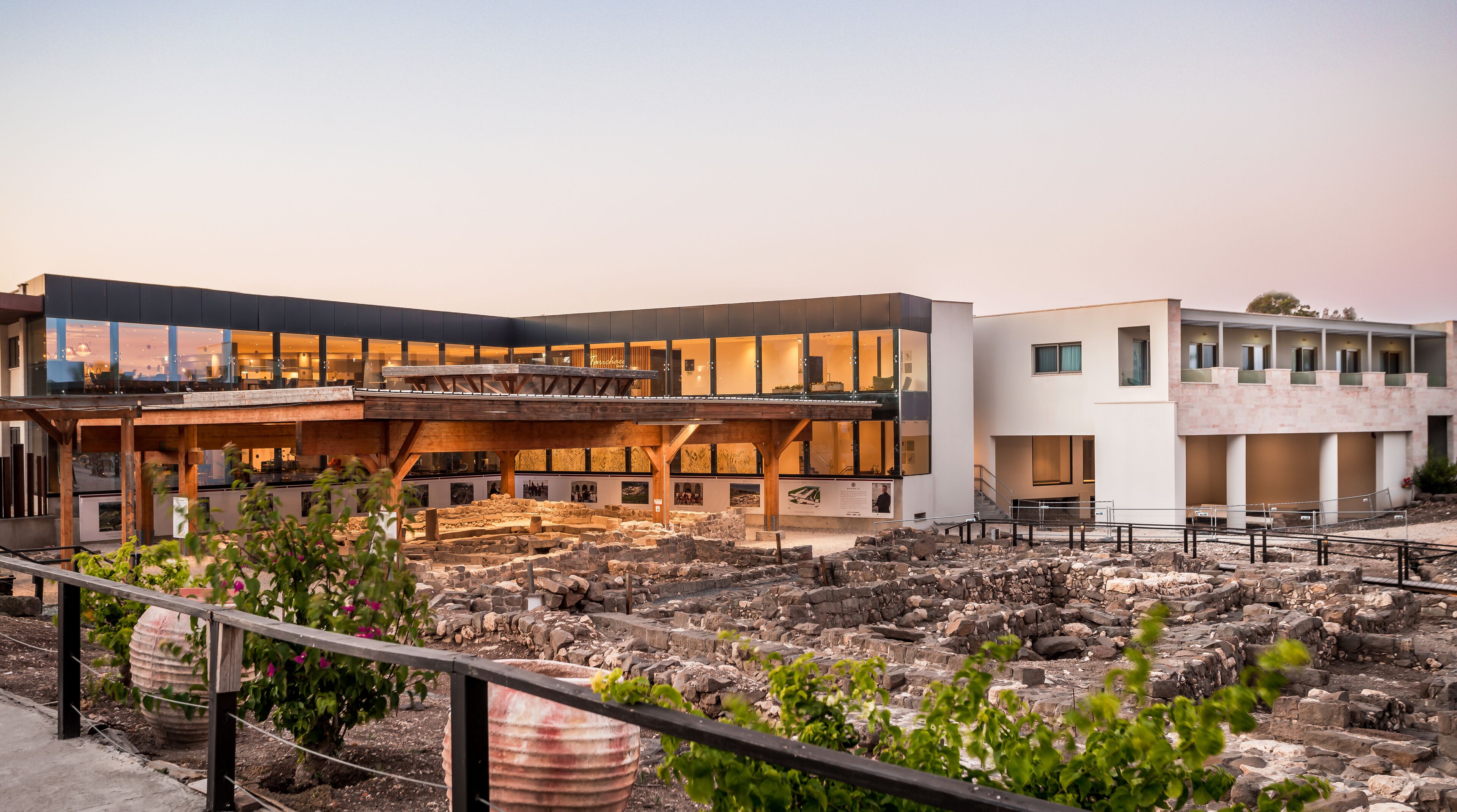 A modern building with a glass facade and a courtyard with ancient ruins.