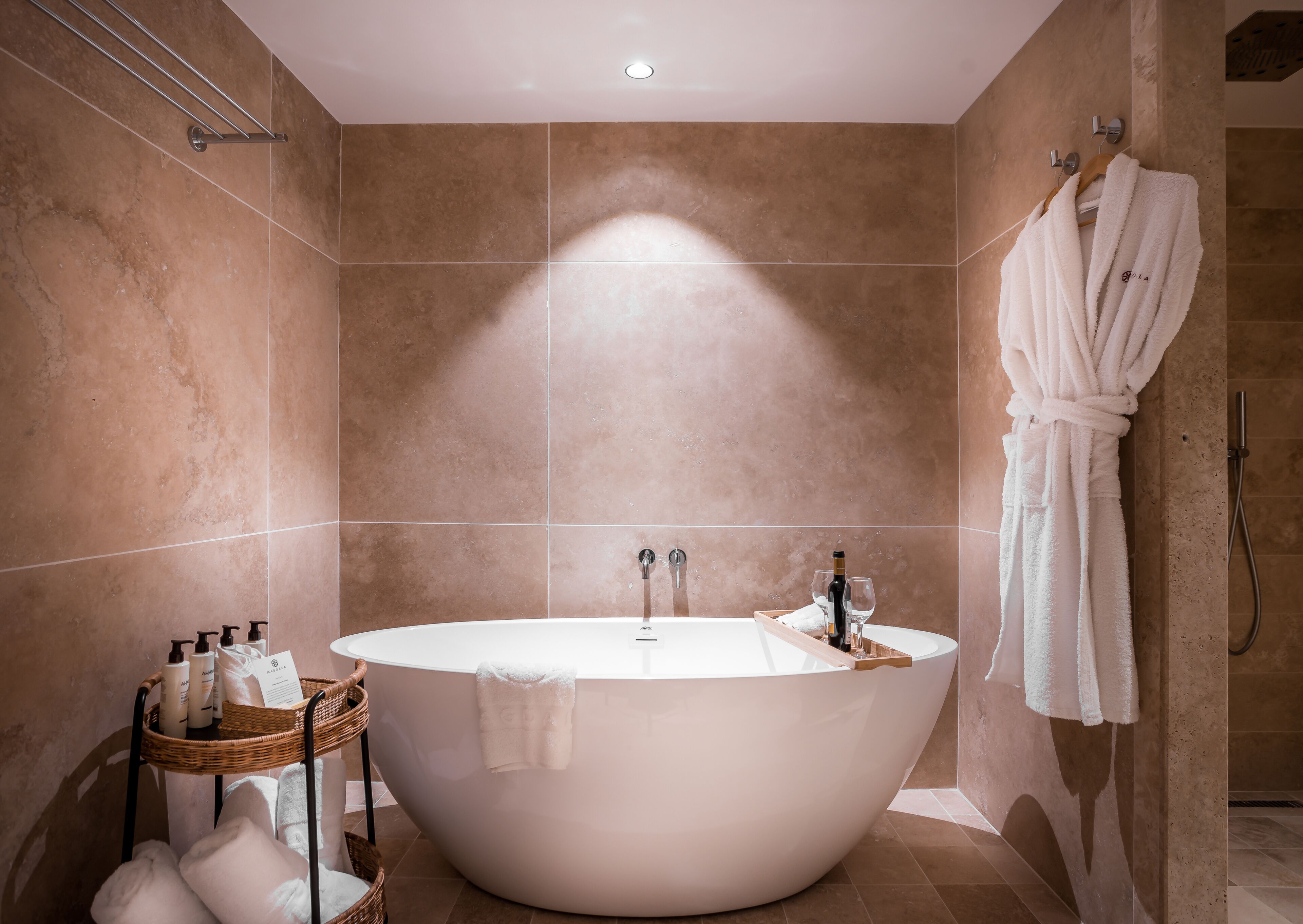 Un bagno moderno con una vasca freestanding, un accappatoio appeso a un gancio e articoli da toilette in un cesto di vimini.