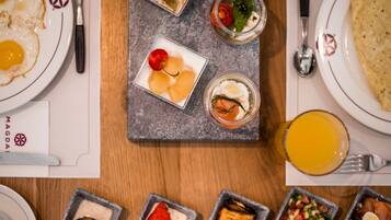 Diversos platos de desayuno en una mesa, como huevos, fruta y un vaso de zumo de naranja.