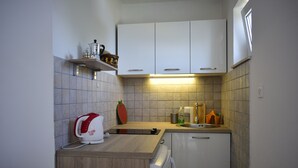 Een kleine keuken met witte kastjes, een houten aanrecht, een koffiezetapparaat, een broodrooster, een spoelbak en een afdruiprek.