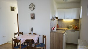 Een compacte keuken met een koelkast, een wastafel en een kleine eethoek met een tafel en stoelen.