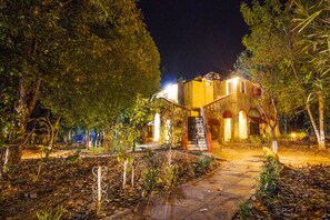 A building with a stone staircase leading to a door, surrounded by trees and a stone pathway. - Jungle King Resort (Bichhiya)