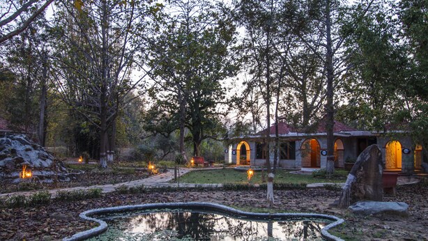 Un jardín tranquilo con un estanque, senderos y un edificio con entradas arqueadas.