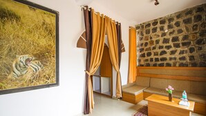 Una habitación con pared de piedra, un sofá, una mesa de centro con un jarrón y una botella, y un cuadro de un tigre.