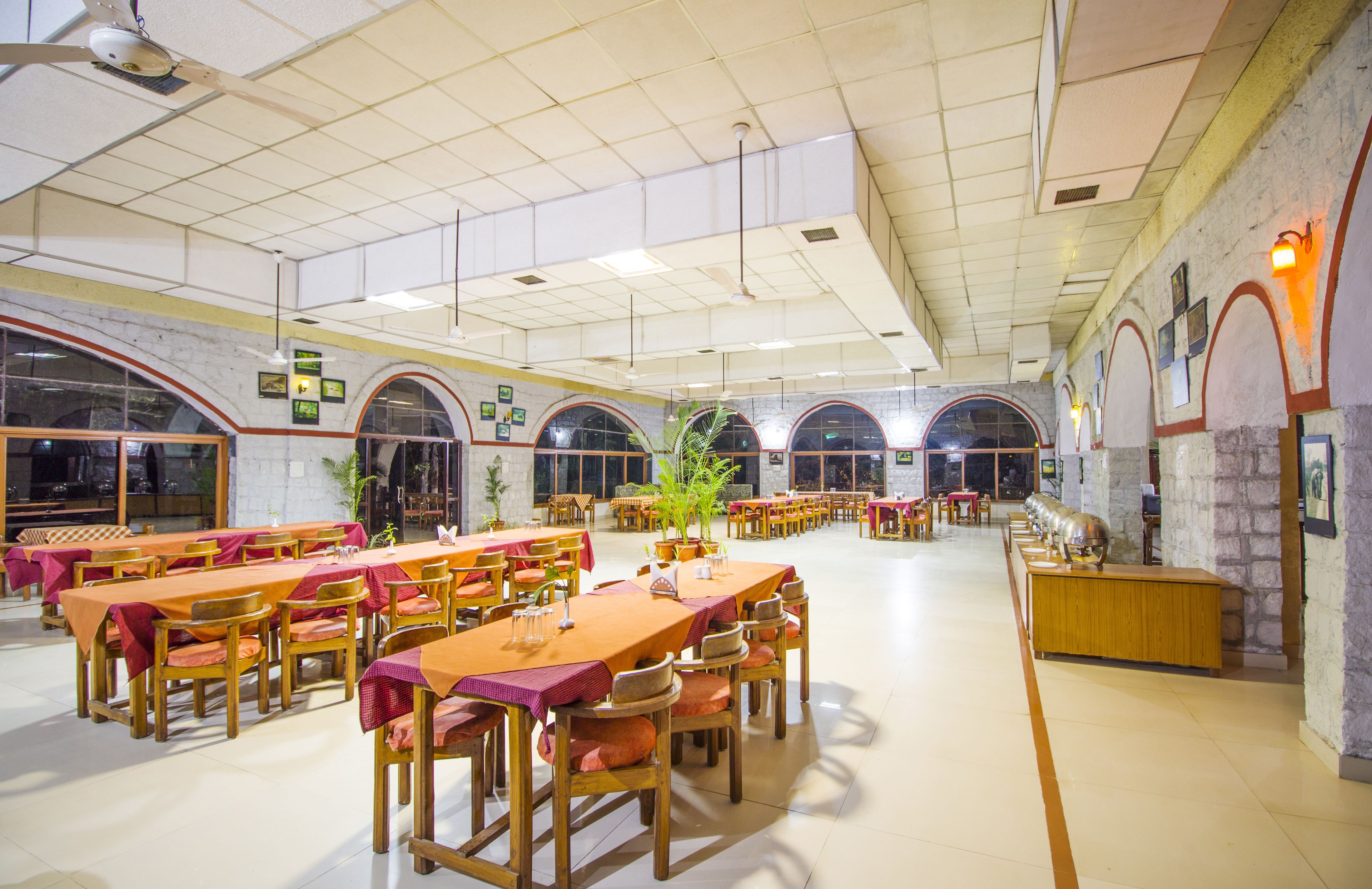 A spacious dining area with multiple tables and chairs, a reception desk, and arched windows.