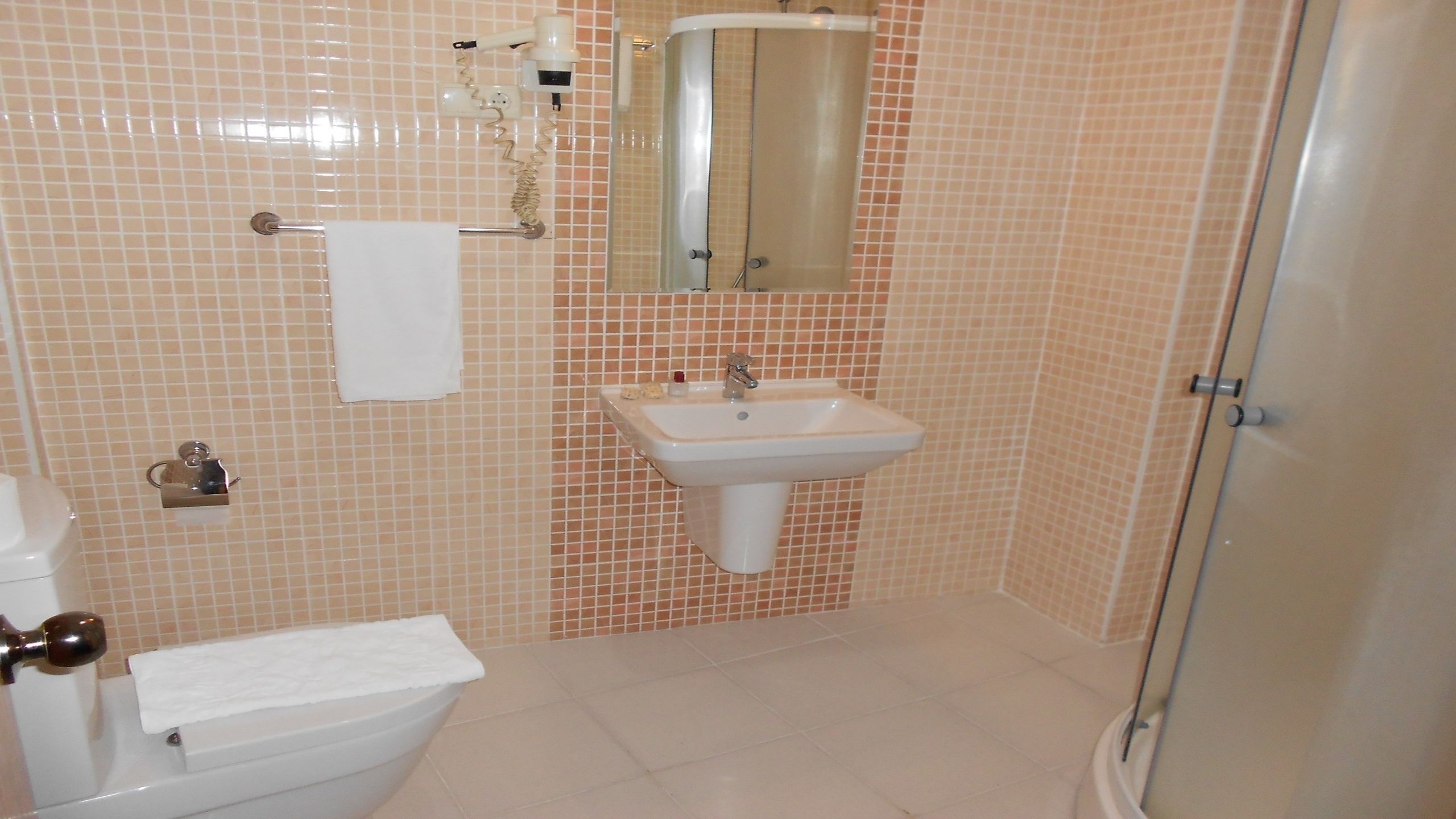 Un baño con inodoro, lavamanos y espejo.