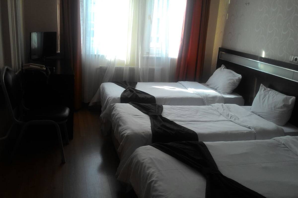 A hotel room with two beds, a desk, and a chair.
