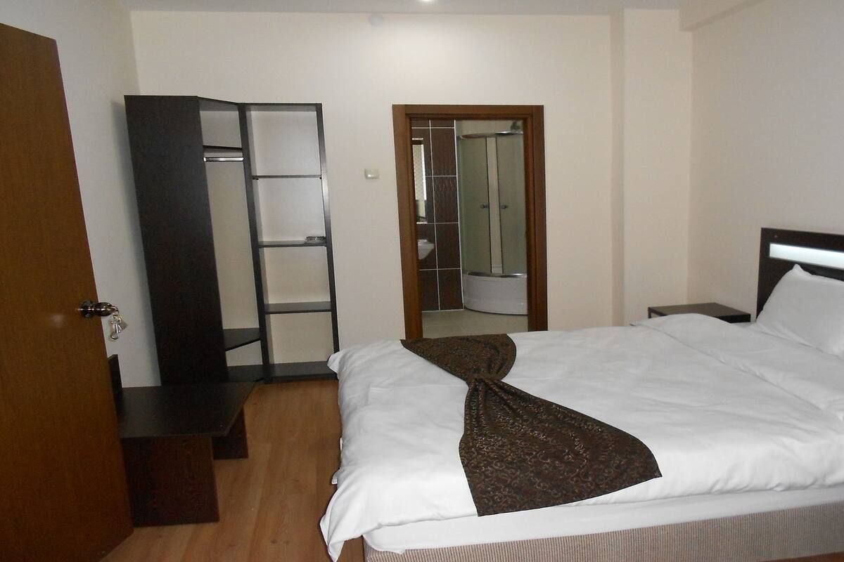 A hotel room with a bed, a wardrobe, a mirror, and a bathroom visible through an open door.
