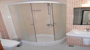 A bathroom with a glass-enclosed shower, a sink, and a toilet. - Nas Hotel (Karaman)