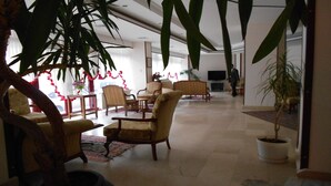 A spacious living area with multiple seating options, a television, and decorative plants. - Nas Hotel (Karaman)