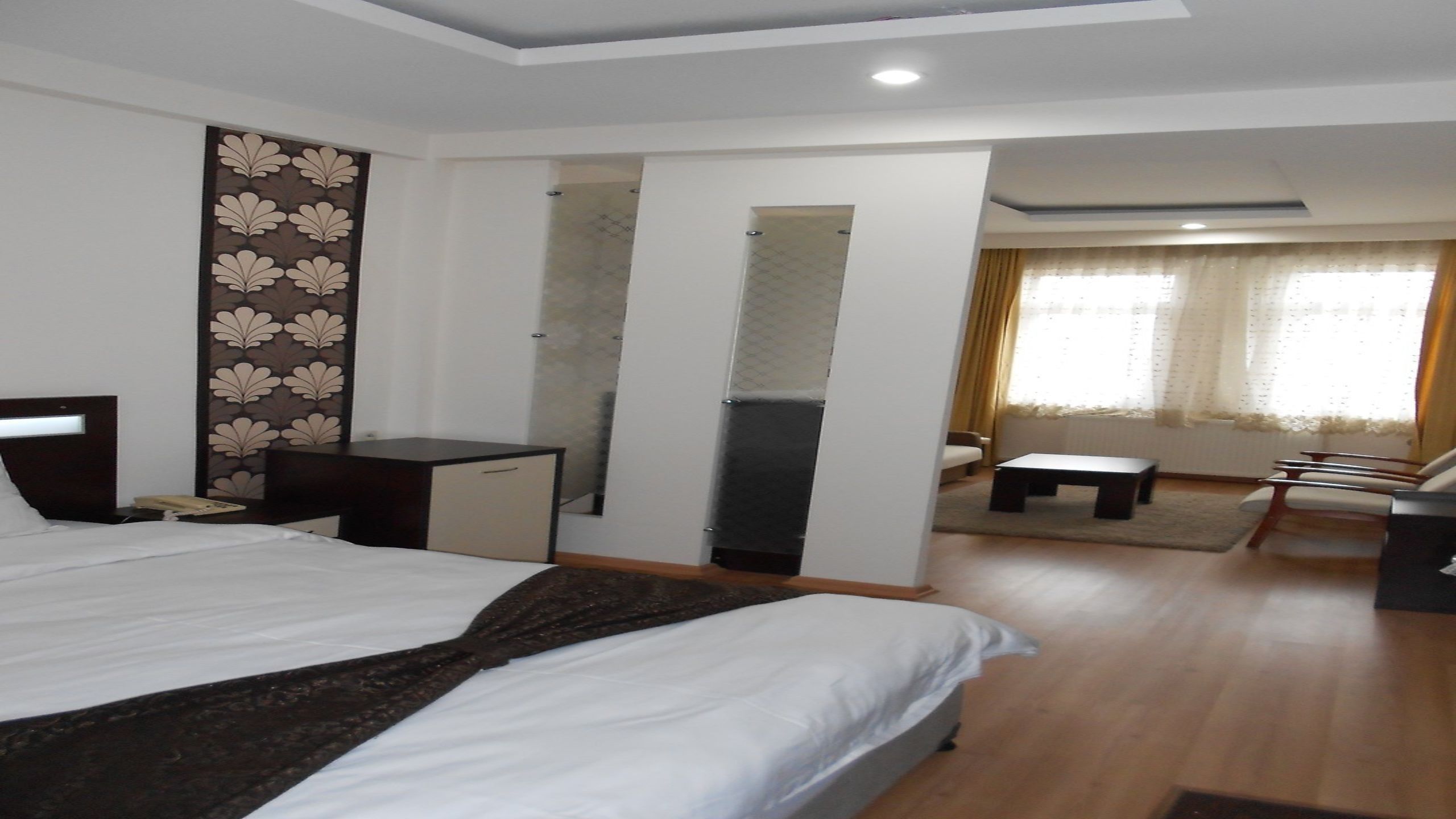A hotel room with a large bed, a desk, a chair, a sofa, and a small table.