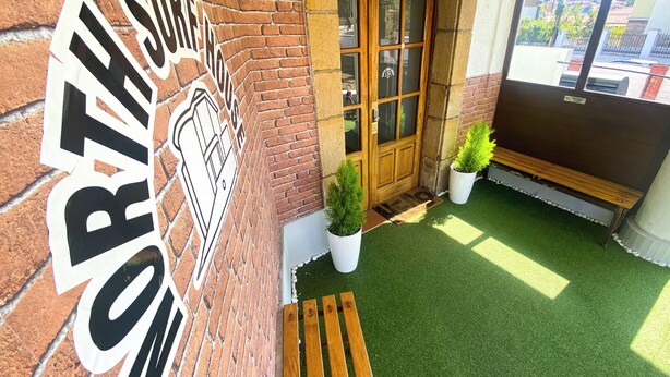 A brick building with a sign reading "SOUTHERN CAFE" and a wooden bench outside. -  North Surf House (Gijon)