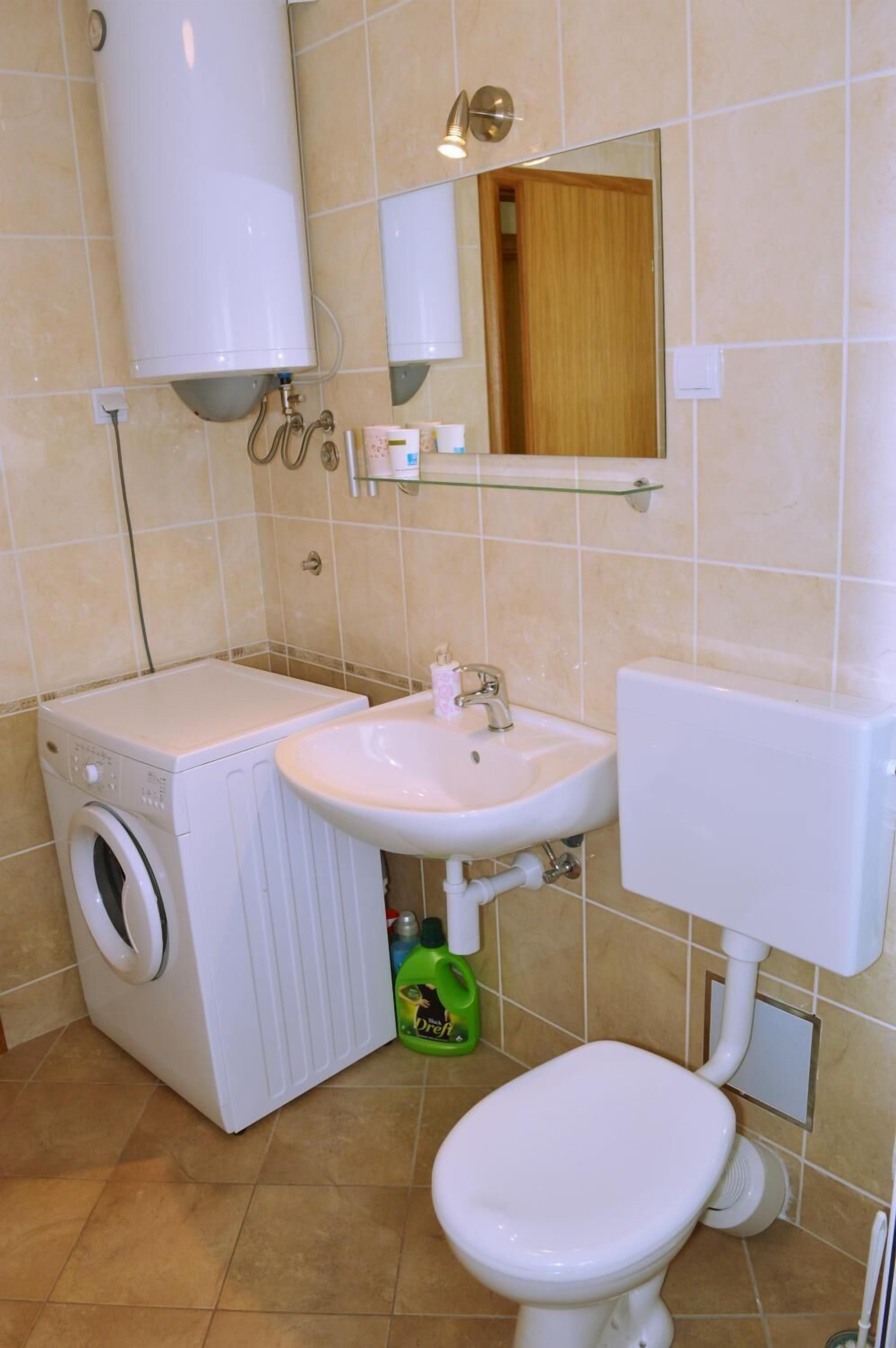 Pieni kylpyhuone, jossa on pesukone, pesuallas ja wc.