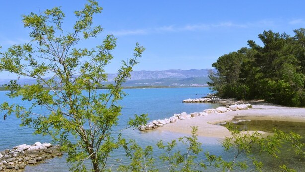A coastal landscape with clear blue water, rocky shorelines, and lush greenery. - Apartment Sunshine (Dobrinj)