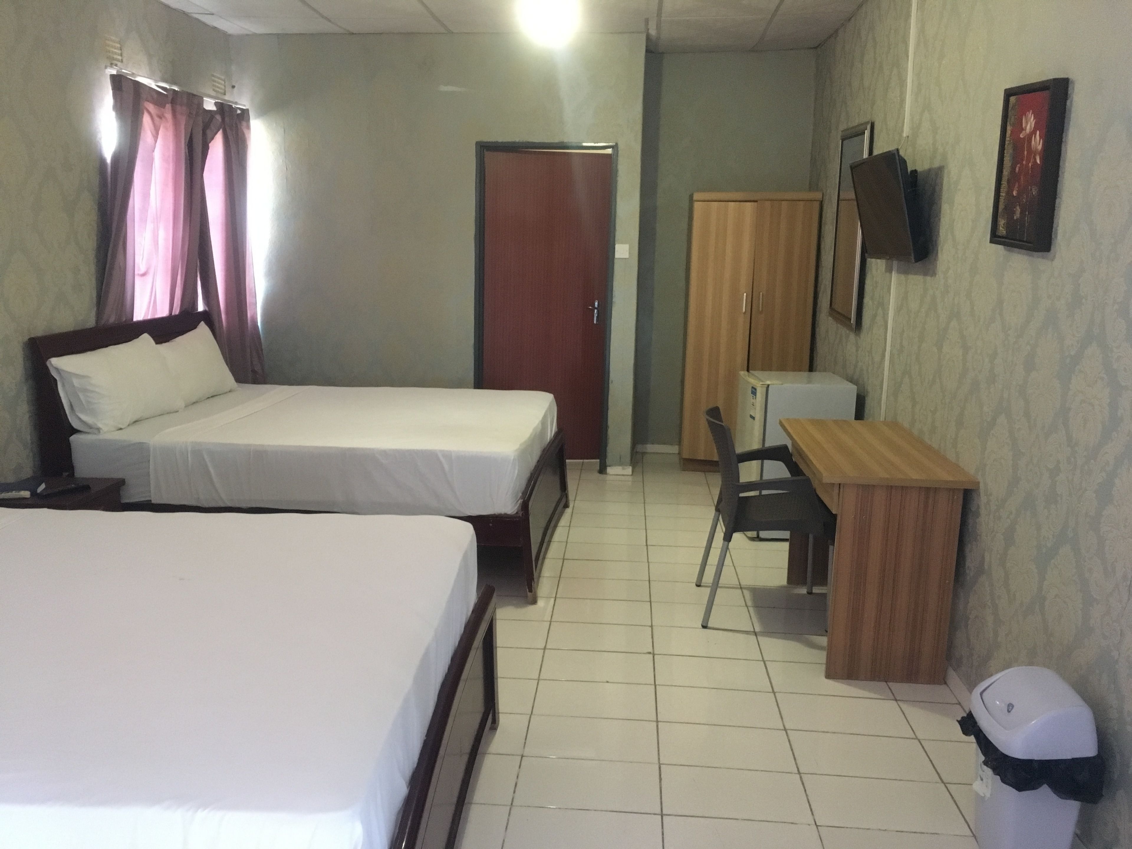 A hotel room with two beds, a desk, a chair, a television, and a wardrobe.