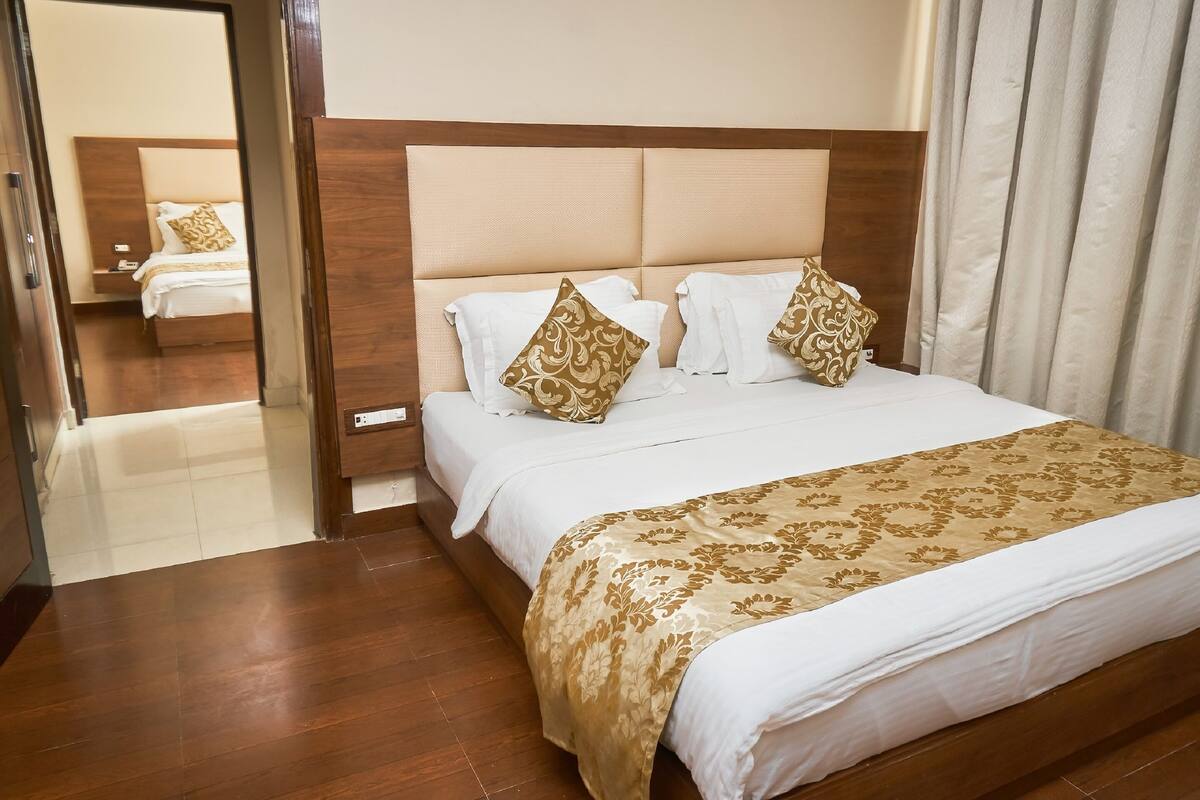 Una habitación de hotel con una cama grande, un cabecero de madera y un espejo que refleja la habitación.
