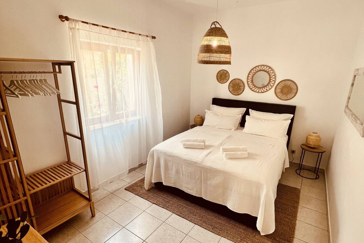Une chambre à coucher avec un lit, une armoire en bois, un luminaire suspendu et une petite table.