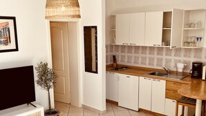 Een moderne keuken met witte kastjes, een houten aanrecht en een hangende rieten lamp.