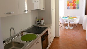 A modern kitchen with white cabinets, a sink, and a dining area with a table and chairs. - RENOVATED THREE-ROOM APARTMENT IN HISTORIC CENTER - IDEAL FOR SMART WORKING (Pizzo)