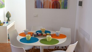 A dining area with a round table, white chairs, and colorful placemats. - RENOVATED THREE-ROOM APARTMENT IN HISTORIC CENTER - IDEAL FOR SMART WORKING (Pizzo)