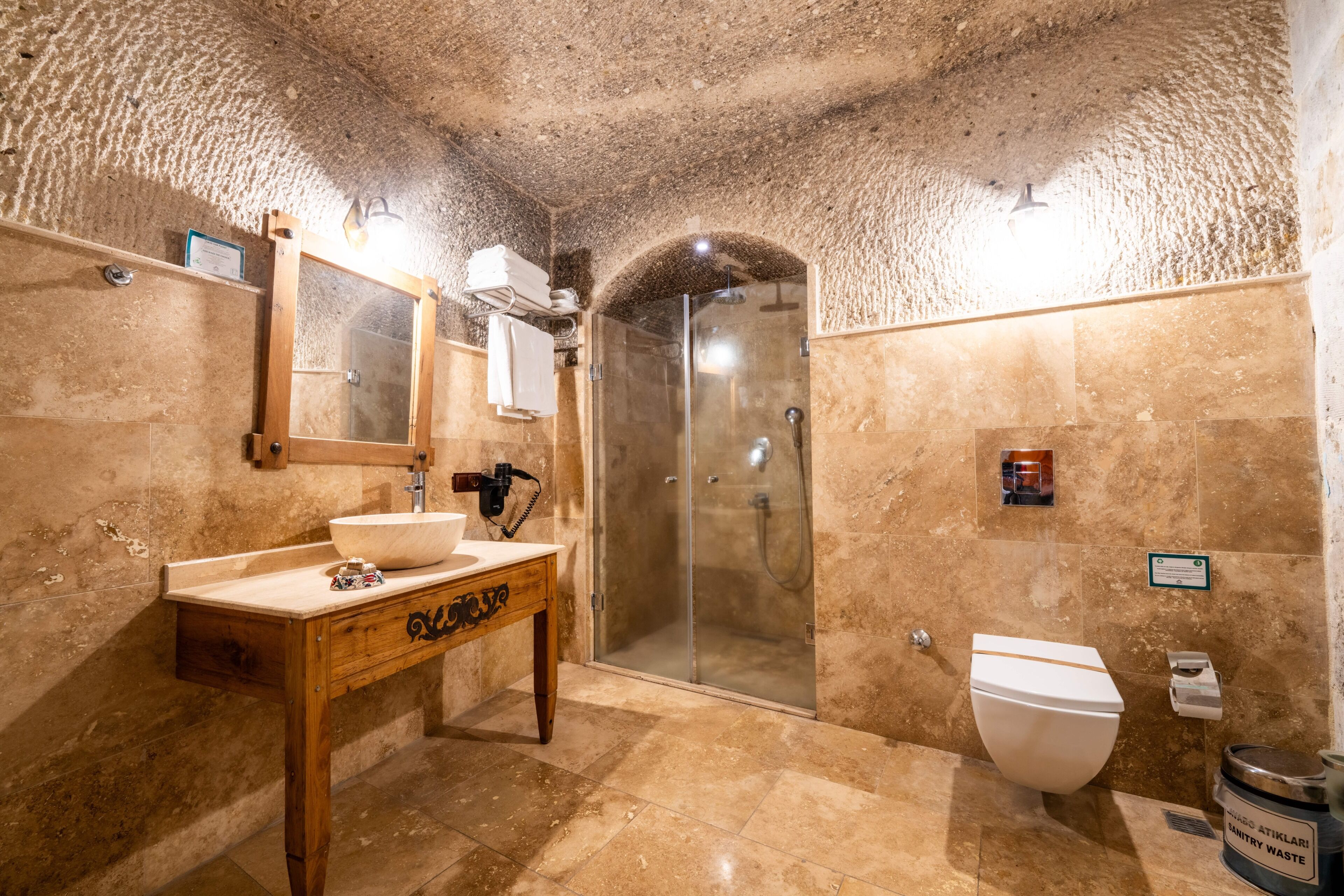 A bathroom with a wooden vanity, a sink, a glass shower enclosure, and a toilet.