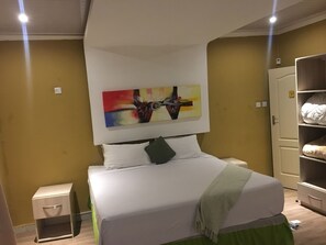 A neatly arranged bedroom with a bed, a bedside table, a wardrobe, and a colorful abstract painting on the wall. - Flower Inn Guest House (Mahalapye)