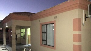 Un edificio con fachada color beige, techo de tejas rojas y una ventana con marco blanco.