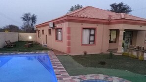 Una casa con piscina, un jardín pequeño y un patio cercado.
