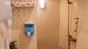 A bathroom with a toilet, a shower, and a decorative tile pattern on the floor.