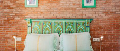A bed with a green headboard, two pillows, and two bedside tables with lamps.