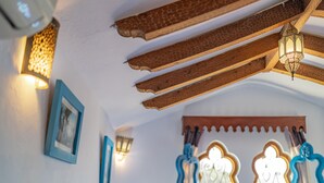 Une chambre à coucher comprenant un lit, des oreillers, une table de chevet, une lampe et deux fenêtres dotées de cadres décoratifs.