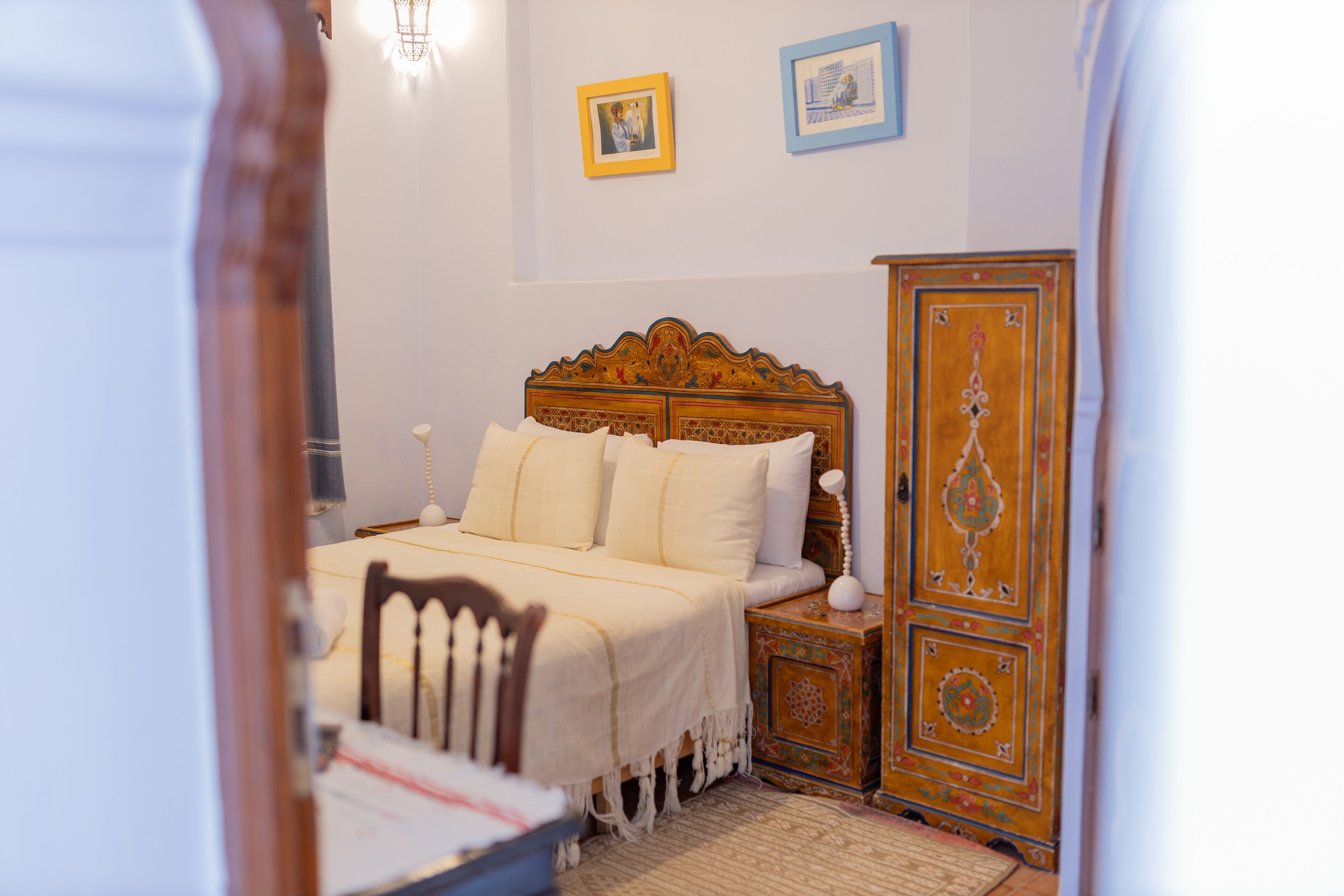 A bedroom with a wooden bed, a nightstand, a chair, and a wardrobe.