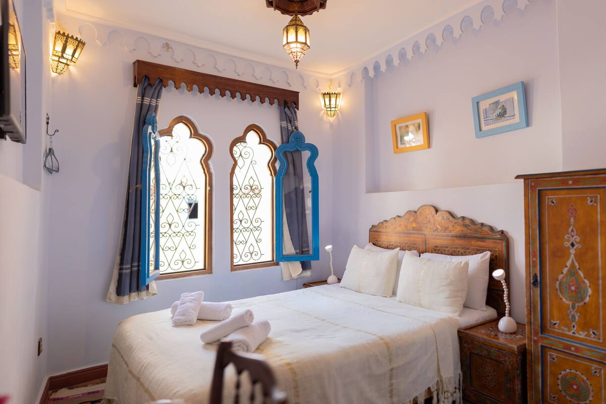 Une chambre à coucher bien rangée, avec un lit, des tables de chevet et une armoire.