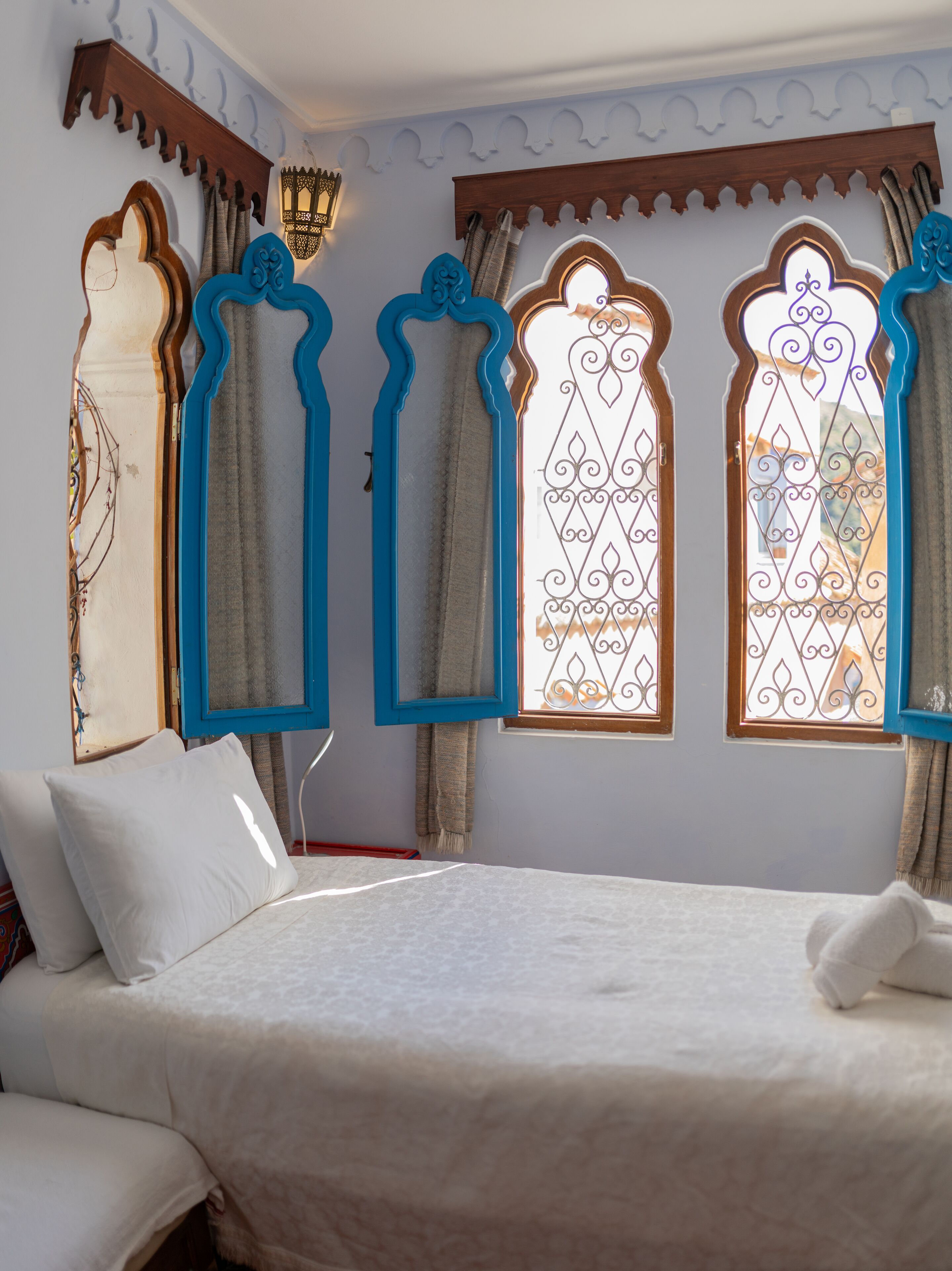A bedroom with a bed, pillows, and curtains.